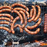 Mehrere goldbraun gegrillte Bratwürste nebeneinander auf dem Rost