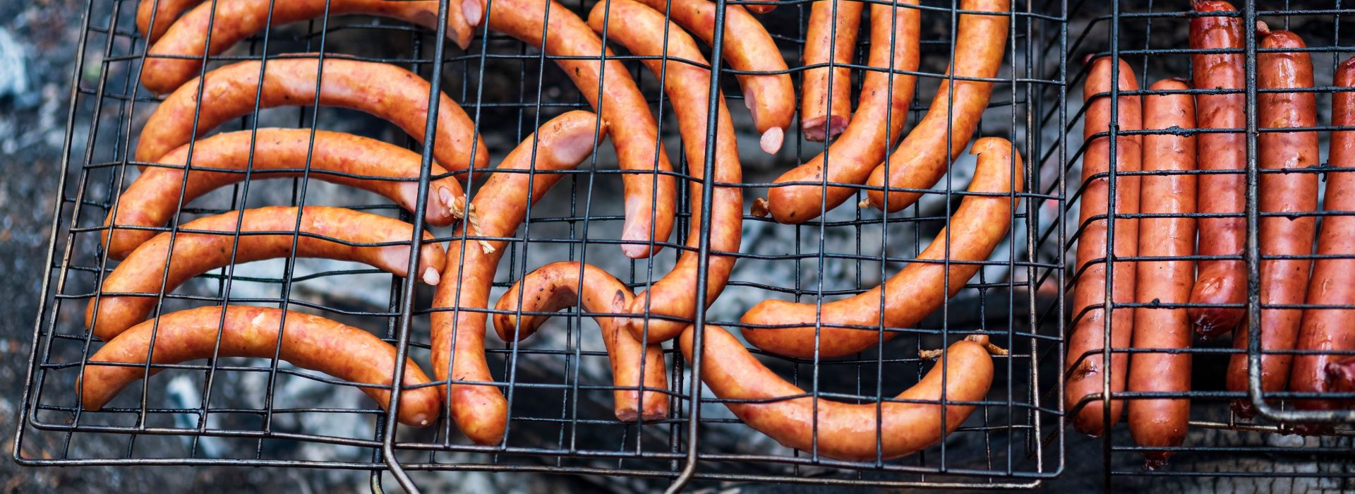 Mehrere goldbraun gegrillte Bratwürste nebeneinander auf dem Rost