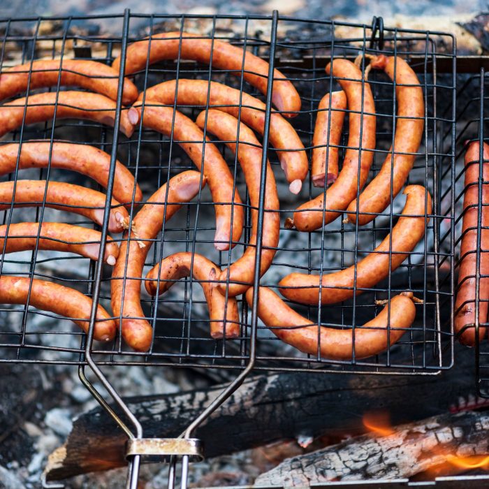 Mehrere goldbraun gegrillte Bratwürste nebeneinander auf dem Rost
