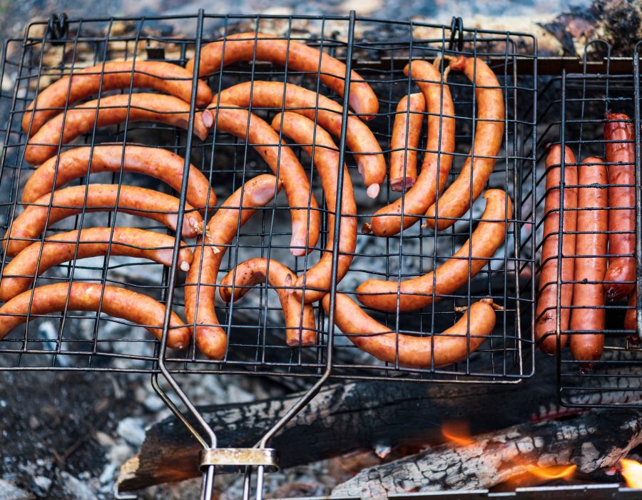 Mehrere goldbraun gegrillte Bratwürste nebeneinander auf dem Rost