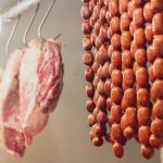 Frische rohe Würste hängen beim Metzger zum Reifen